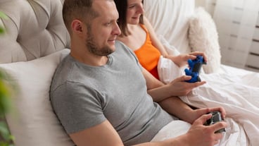 Couple playing videogames in bed
