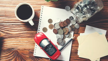 Coins in glass jar with car model