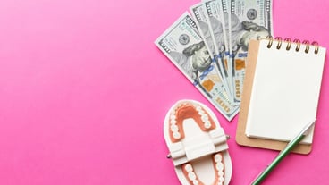 Flat lay composition with an educational dental typodont model and money with a notebook on a colored tabletop view. Expensive treatment.