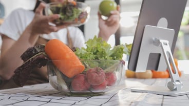 Delicious fruit and vegetables on a table and woman cooking Housewife is cutting green cucumbers on a wooden board for making fresh salad in the kitchen