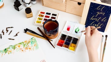Girl painting flowers on paper with watercolor.