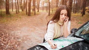 Young woman alone car traveler with map. Close up Hand. Autumn concept. Autumn forest journey by car
