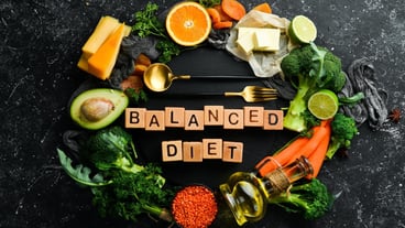 Balanced diet inscription Avocado carrot orange broccoli dried fruits nuts and parsley Top view Free space for your text