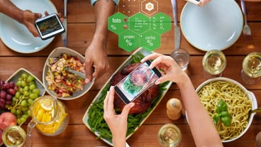 hands with smartphones and food on table