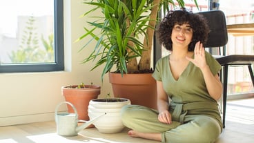 Young pretty arab woman at home, with a watering can and plants