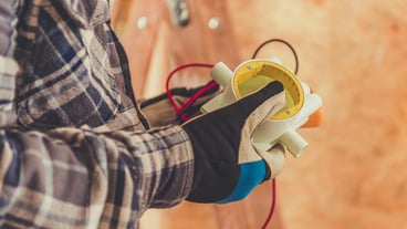 Technician Measures Electrical Current With a Multimeter in a Construction Setting During Daylight Hours