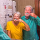Couple of two happy and smiling seniors brushing their teeth of they each other together at home in the bathroom - self care and taking care of theyself