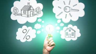 Businessman hand holding abstract glowing light bulb with house sketch on green background Real estate and mortgage concept
