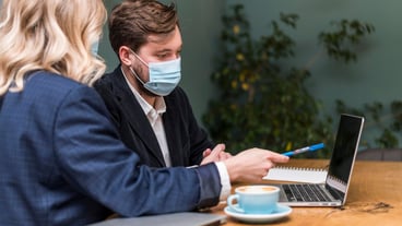 Man and woman talking about a new project while wearing medical masks