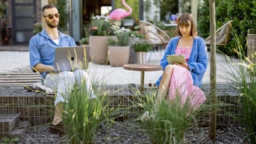 Couple work on gadgets at the garden
