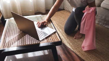 Woman workout with rubber resistance band while watching online workout tutorials on laptop at home