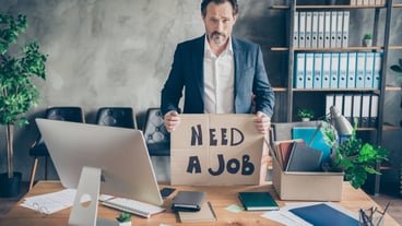 Photo of despair sad layoff dismissed worker mature jobless guy hold placard poster search job world crisis ruined career workplace fired packing stuff modern office desktop table indoors