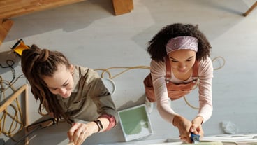 Two young workers painting wall of cafe
