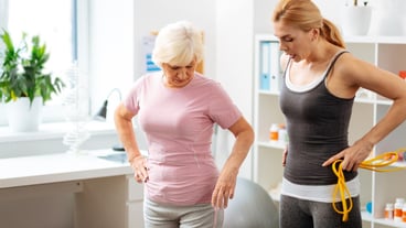 Practicing sport. Good looking fit woman holding a rubber band while speaking about new exercise with her patient