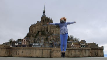 Woman in jump against the mont saint michel in france