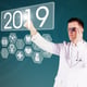 Digital composite image of doctor touching number 2019 against a blue background