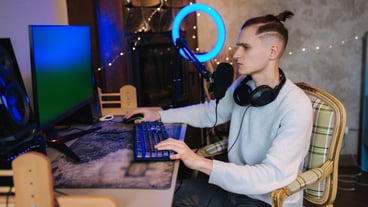 Happy young man in headset with pc computer playing game at home and streaming playthrough
