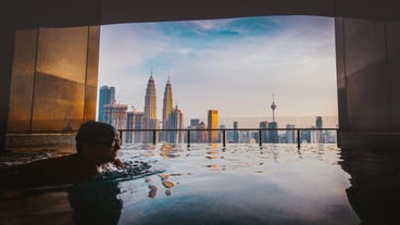 Man swimming in infinity pool against buildings