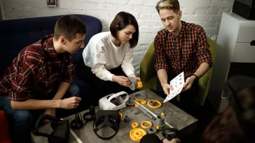 A team of four creative engineers work with virtual reality, a young woman tests VR glasses in an office space.