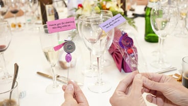 Closeup shot of people holding thank you souvenirs around the table