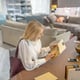 Choice, thought. Woman with a bag on her shoulder, holding wood samples for furniture in her hands, sitting at a table in a furniture showroom, choosing, serious.
