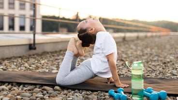 Young girl practicing advanced yoga pose outdoors at sunset exercise on rooftop demonstrating