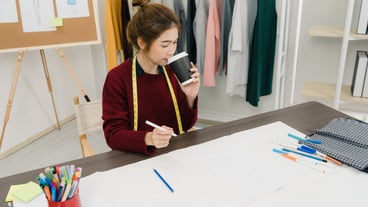 Professional beautiful Asian female fashion designer working with fabric sketches