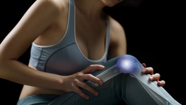 Woman holds her hands to the knee, pain in the knee highlighted in blue, medicine, massage concept.