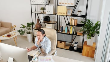 Serious frowning freelance graphic designer working on computer at table in his home office