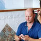 Tattoo master mehendi makes a henna tattoo drawing on the scalp of a bald Caucasian man.