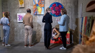 Young blonde woman talking to mature, elegant man in art gallery