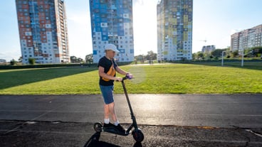 A boy rides a scooter along a path in the city