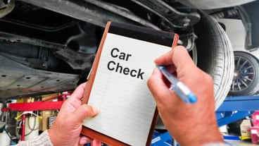 Inspection of the car in a car repair shop by an employee or a car mechanic with notes in a notebook