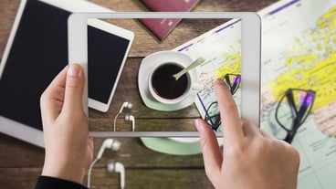 Cropped hands photographing coffee cup and map from digital tablet
