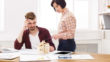 Two colleagues discussing architectural project, working with blueprints in modern workplace interior, copy space