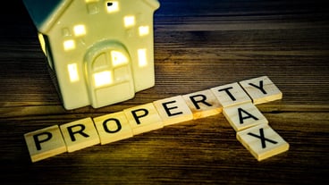 home property tax in wooden letters and a ceramic house with lights on