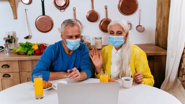 Senior couple wearing mask video calling in laptop at home