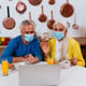 Senior couple wearing mask video calling in laptop at home