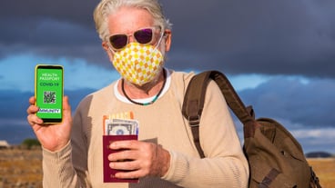 Senior man wearing protective face mask shows health passport app for people vaccinated against coronavirus, ready to travel again