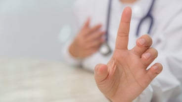 그녀의 검지 손가락을 보여주는 의사의 손 클로즈업