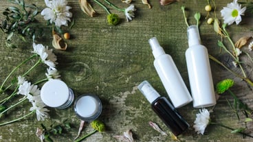 Cosmetic spray dispenser and flowers on a wooden background