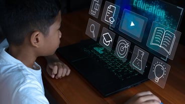Close up The boy sits staring at the laptop and his hand is holding the mouse educational.
