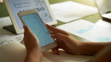 Cropped unrecognizable person analysing financial chart on smartphone