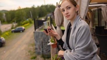 Woman hand holding glass with wine on blurred natural background.