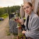 Woman hand holding glass with wine on blurred natural background.
