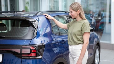 Beautiful mature woman shopping for new car at auto dealership
