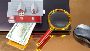 Finding and buying a home over the Internet House model on the background of a laptop and a magnifying glass