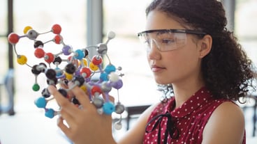 Attentive schoolgirl experimenting molecule model in laboratory