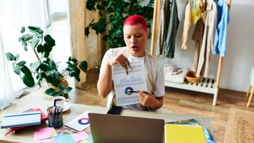 A young woman engaged in remote learning at home surrounded by colorful notes and plants