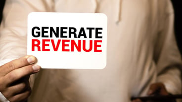 Card with text GENERATE REVENUE in the hand of a businessman